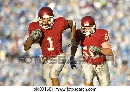 Football players running on field in game View Large Photo Image Stock Image - Football players running on field in game. Fotosearch
