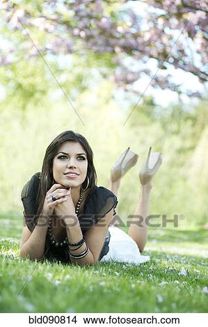 Picture - Glamorous Caucasian woman laying in grass. Fotosearch