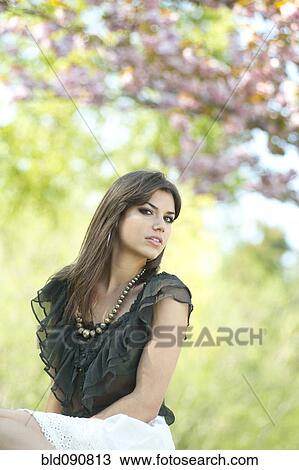 Stock Image - Glamorous Caucasian woman sitting outdoors. Fotosearch