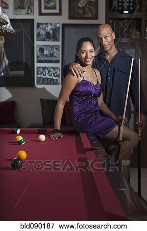 Stock Photo - Glamorous couple playing pool in bar. Fotosearch
