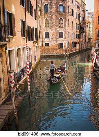 Stock Photograph - Gondolier rowing gondola in canal. Fotosearch