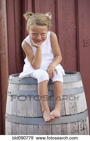 Grinning Caucasian girl sitting on barrel View Large Photo Image Stock Photo - Grinning Caucasian girl sitting on barrel. Fotosearch