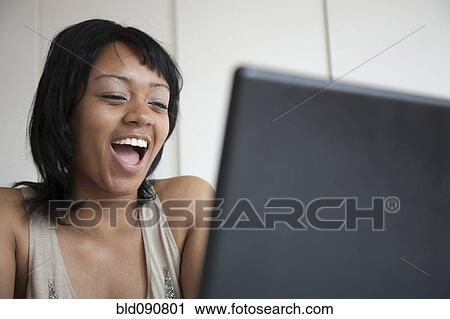 Grinning woman looking at laptop View Large Photo Image Stock Image - Grinning woman looking at laptop. Fotosearch