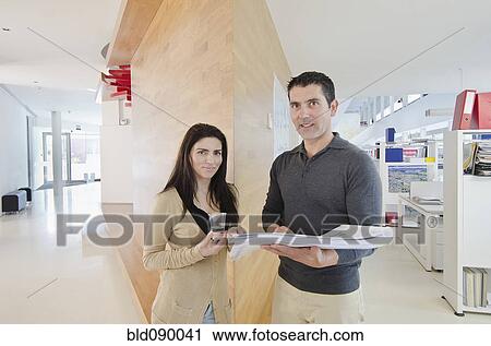 Stock Image - Hispanic business people looking at paperwork together. Fotosearch