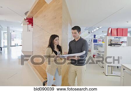Stock Photo - Hispanic business people looking at paperwork together. Fotosearch