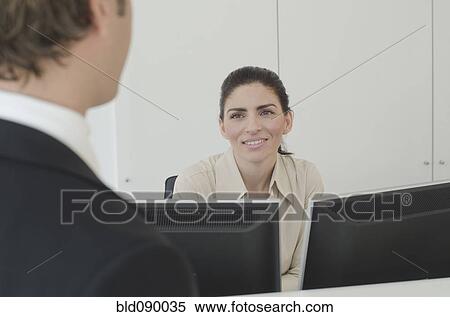 Stock Photography - Hispanic businessman talking to receptionist. Fotosearch