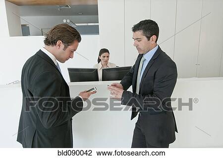 Hispanic businessmen holding cell phones in office View Large Photo Image Stock Image - Hispanic businessmen holding cell phones in office. Fotosearch