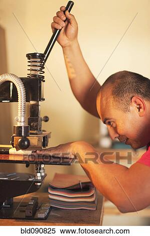 Stock Photography - Hispanic man operating book-binding machine. Fotosearch