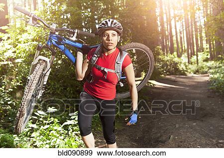 Hispanic woman carrying mountain bike in forest View Large Photo Image Stock Photo - Hispanic woman carrying mountain bike in forest. Fotosearch