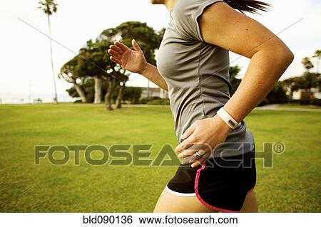 Stock Photograph - Hispanic woman running in park field. Fotosearch