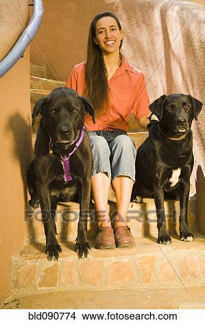 Picture - Hispanic woman sitting steps with dogs. Fotosearch