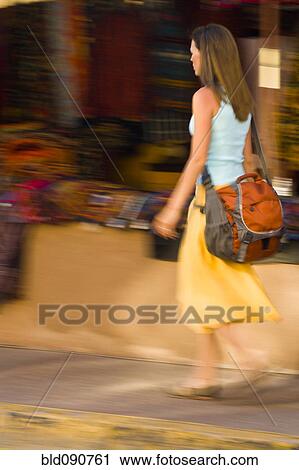 Stock Image - Hispanic woman walking on sidewalk. Fotosearch