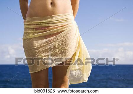 Stock Photography - Hispanic woman wearing sarong near ocean. Fotosearch