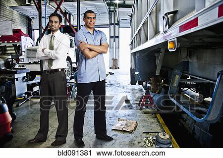 Stock Image - Manager and mechanic standing in auto repair shop. Fotosearch
