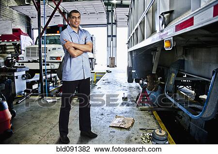 Mechanic standing in auto repair shop View Large Photo Image Stock Image - Mechanic standing in auto repair shop. Fotosearch