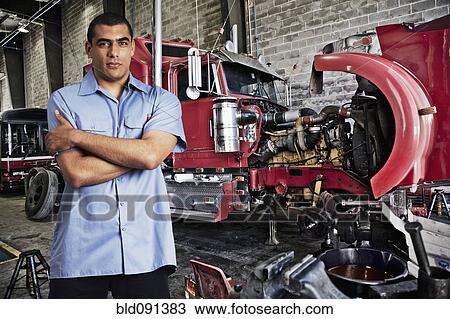 Stock Image - Mechanic standing in auto repair shop. Fotosearch