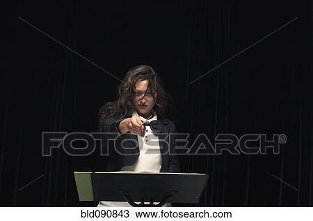 Stock Image - Mixed race conductor pointing baton. Fotosearch