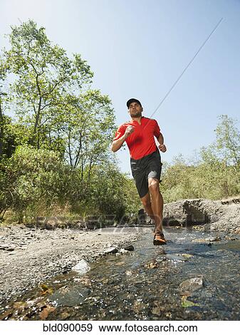 Stock Photo - Mixed race man running through stream. Fotosearch