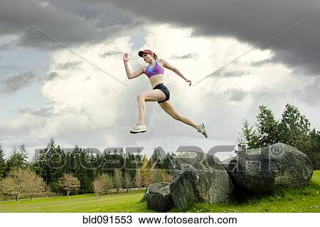 Stock Image - Mixed race teenager jumping from rock. Fotosearch