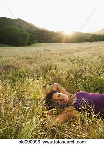 Stock Photograph - Mixed race woman laying in remote field. Fotosearch