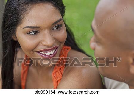 Picture - Mixed race woman looking at boyfriend. Fotosearch