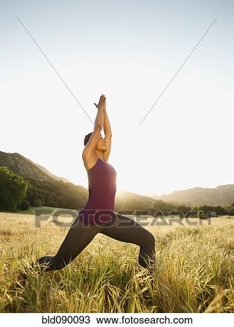 Stock Image - Mixed race woman practicing yoga in remote area. Fotosearch