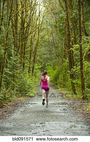 Stock Image - Mixed race woman running on remote path. Fotosearch