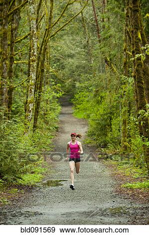 Stock Photo - Mixed race woman running on remote path. Fotosearch