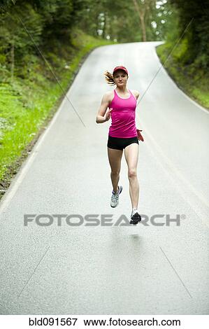 Stock Photo - Mixed race woman running on remote road. Fotosearch