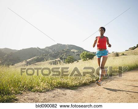 Stock Image - Mixed race woman running on remote trail. Fotosearch