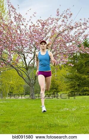 Stock Image - Mixed race woman running outdoors. Fotosearch