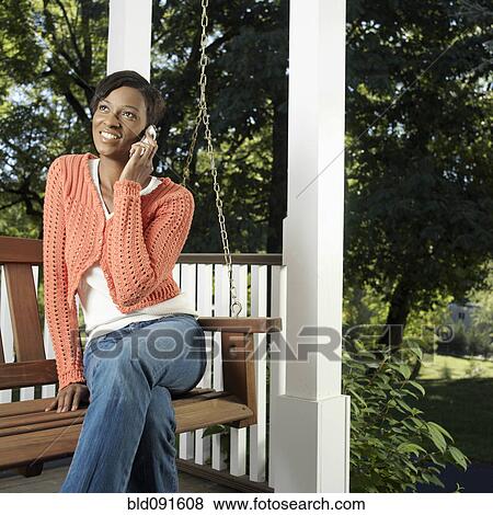 Stock Photo - Mixed race woman using cell phone on porch. Fotosearch