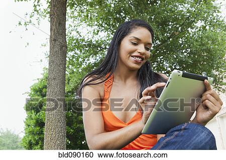 Mixed race woman using digital tablet outdoors View Large Photo Image Stock Image - Mixed race woman using digital tablet outdoors. Fotosearch