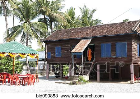 Stock Image - Monk standing at temple doorway. Fotosearch