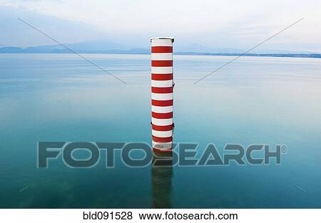 Stock Photo - Red and white stripe pillar in tranquil lake. Fotosearch