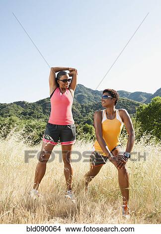 Picture - Runners stretching together in field before exercise. Fotosearch