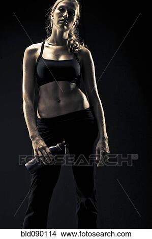 Picture - Serious athletic woman in sportswear holding water bottle. Fotosearch