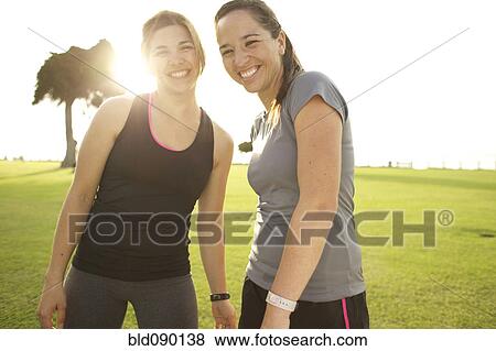 Stock Photo - Smiling athletic friends standing together in field. Fotosearch