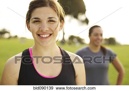 Stock Photo - Smiling athletic friends standing together in field. Fotosearch