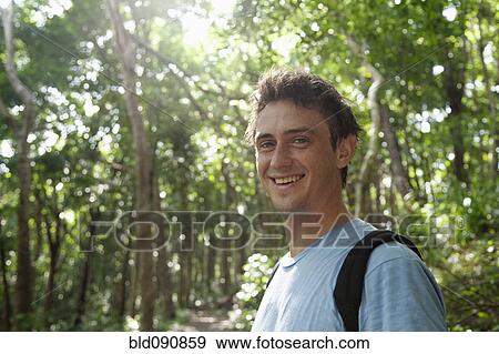 Stock Photo - Smiling Caucasian man standing in forest. Fotosearch