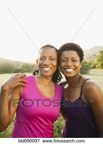 Stock Photo - Smiling friends hugging outdoors. Fotosearch
