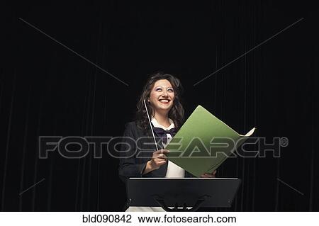 Stock Image - Smiling mixed race conductor holding folder. Fotosearch