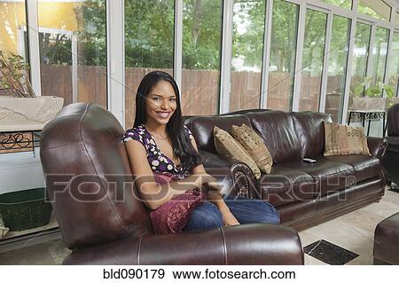 Stock Photo - Smiling mixed race woman sitting in armchair. Fotosearch