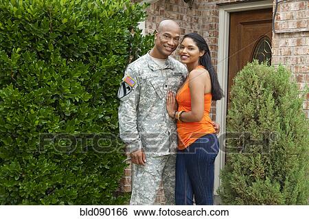 Stock Photograph - Smiling soldier and wife hugging at front door. Fotosearch