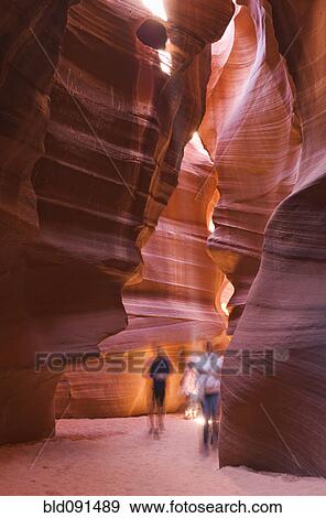 Stock Photo - Tourists visiting unusual, orange rock formations in cave. Fotosearch