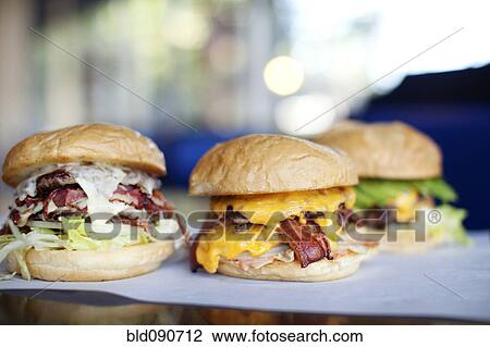 Stock Image - Various indulgent cheeseburgers in diner. Fotosearch