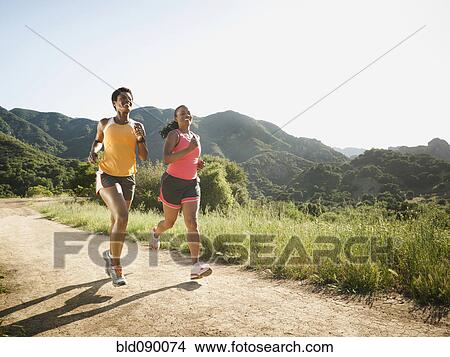 Picture - Women running together on remote trail. Fotosearch