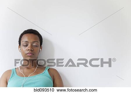 Stock Image - African American woman listening to music on earbuds. Fotosearch