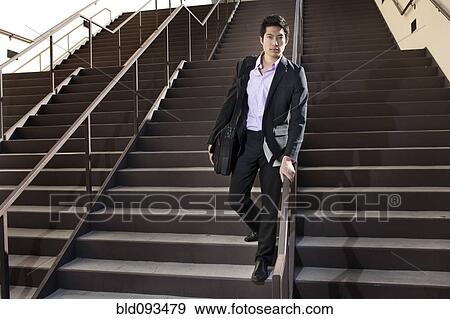 Stock Photo - Asian businessman descending staircase. Fotosearch