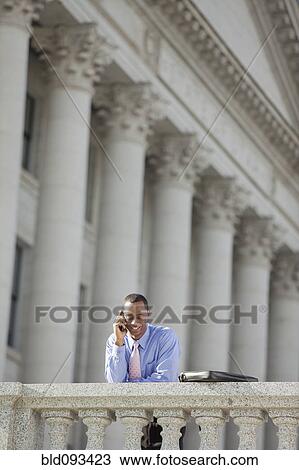 Stock Image - Black businessman talking on cell phone outdoors. Fotosearch